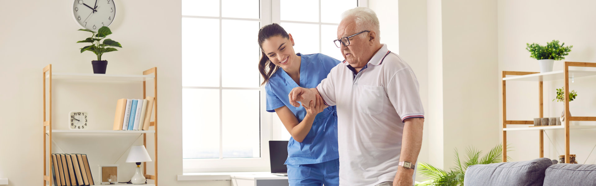 Smiling caregiver helping senior man to stand up and walk