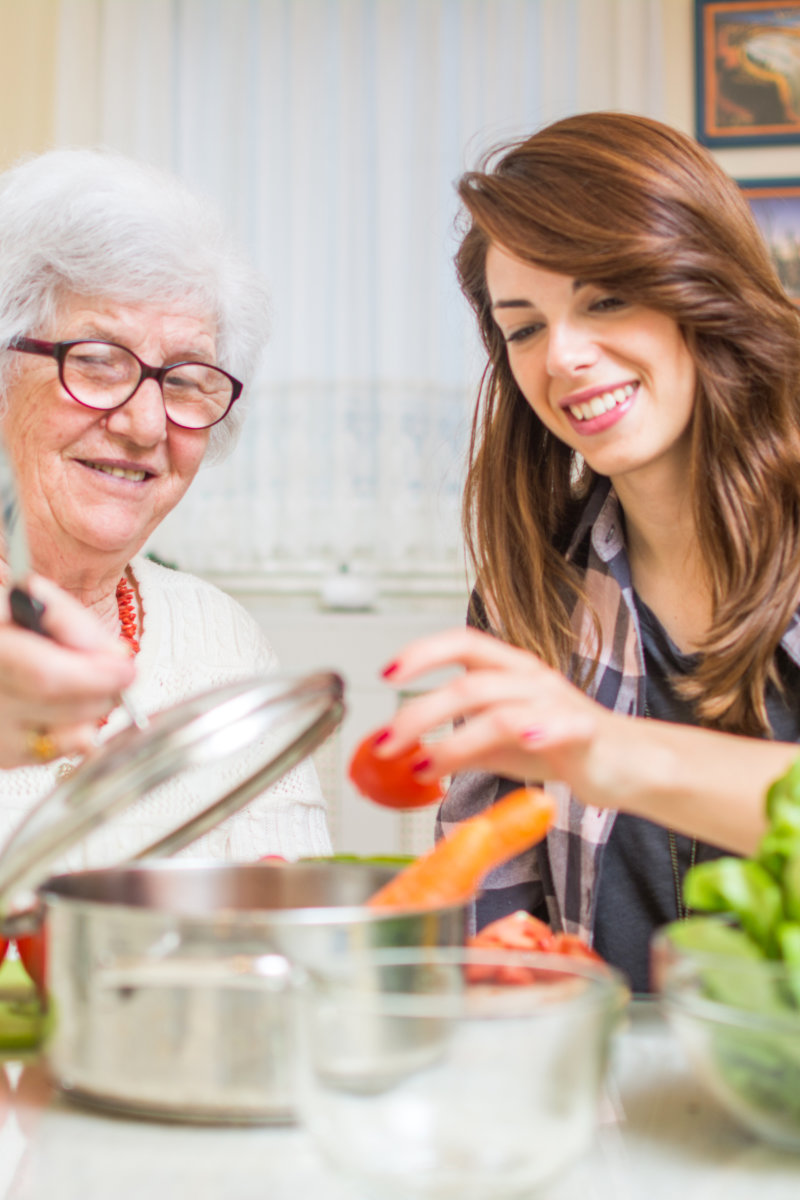 Grandmother and her granddaughter preparing healthy food together in the kitchen.
