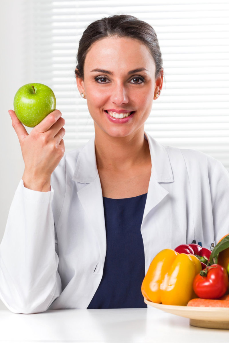 female doctor smiling holding fruit